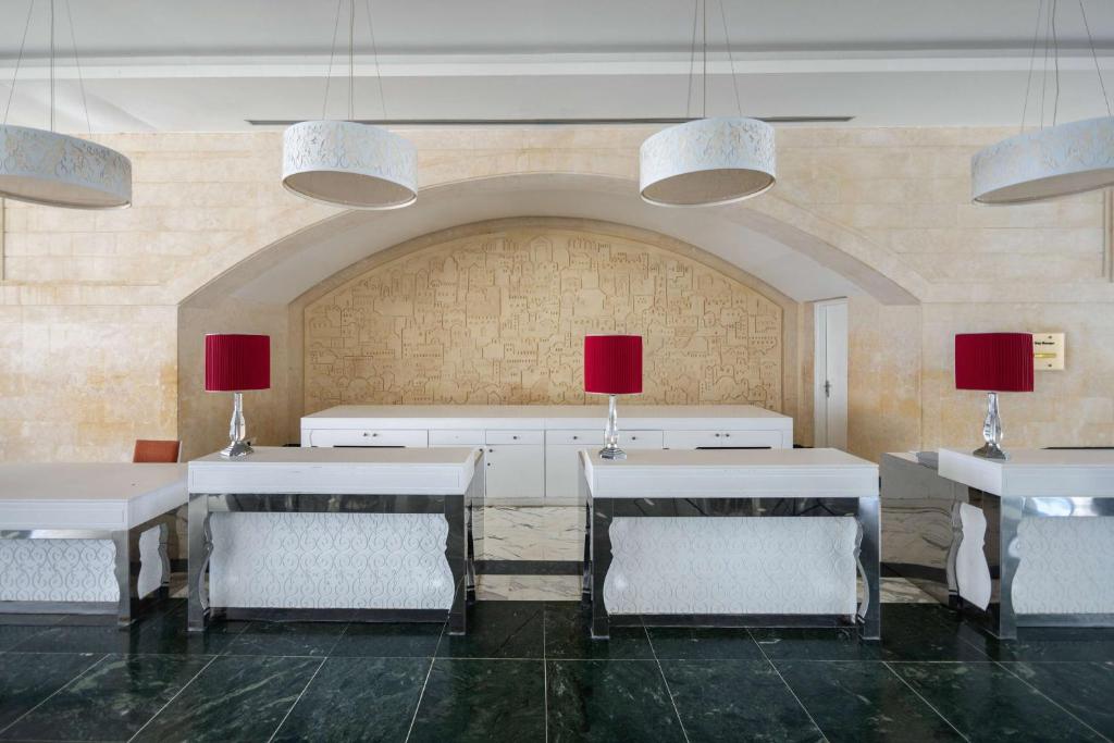 a dining room with white tables and chairs and red lamps at Radisson Blu Resort & Thalasso Hammamet in Hammamet