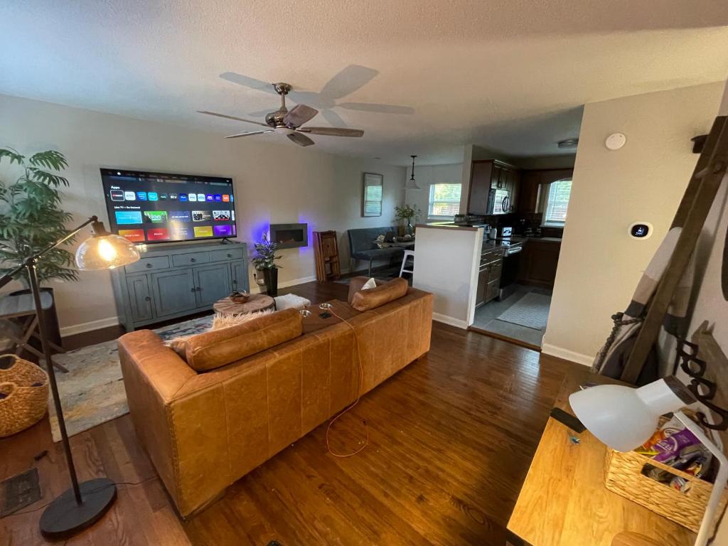 a living room with a couch and a flat screen tv at Hidden Gem! The Hogspitality House - 3 Bedroom - 5 min from the University of Arkansas! in Fayetteville