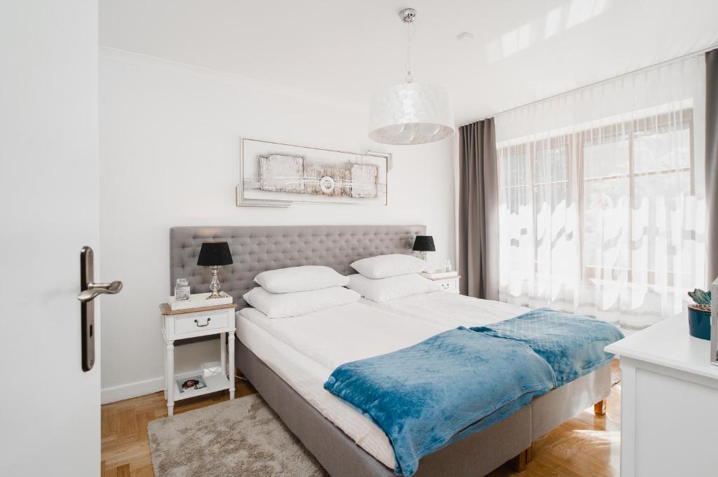 a white bedroom with a large bed and a window at Apartament Marta Luxury in Krynica Morska
