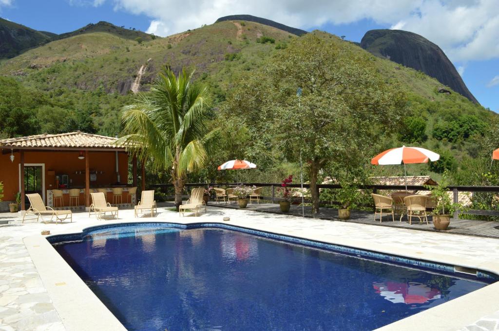uma piscina de resort com uma montanha ao fundo em Artesanal Gourmet e Pousada em Posse