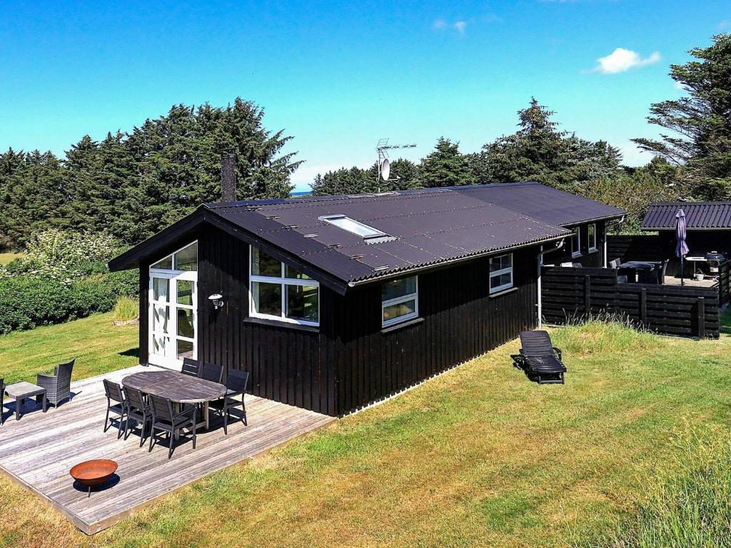 a black house with a picnic table and a deck at 6 person holiday home in Hirtshals in Hirtshals