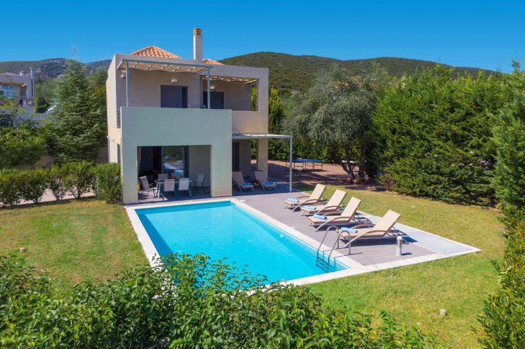 a villa with a swimming pool in front of a house at Villa Rubi by Villa Plus in Karavomylos