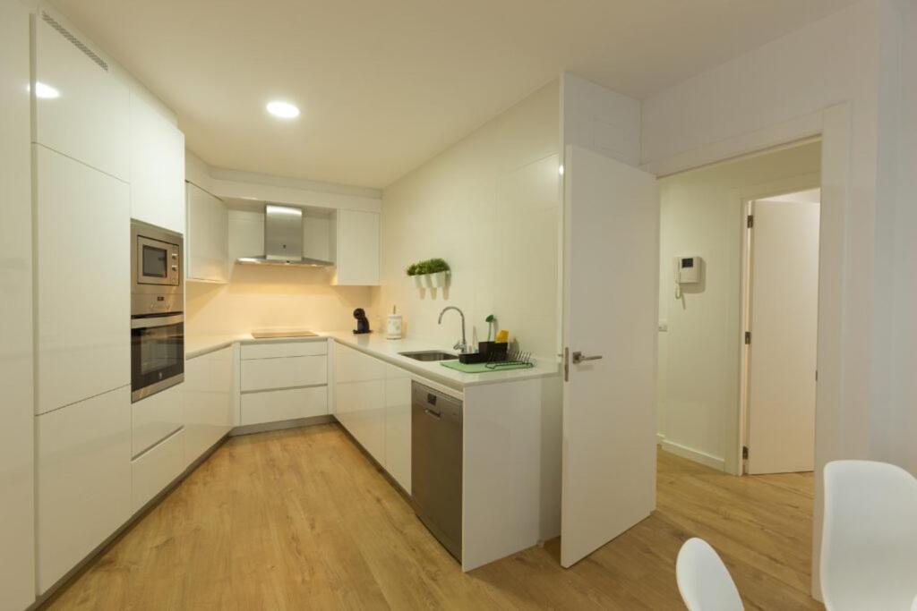 una cocina blanca con armarios blancos y fregadero en Apartamento Confot / SBHome, en Noia