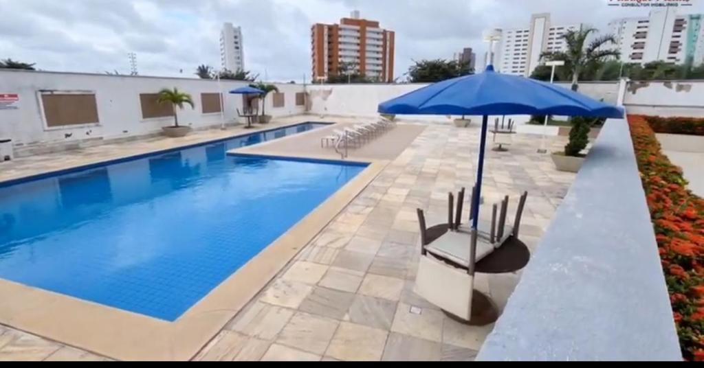 a large swimming pool with an umbrella and chairs at APARTAMENTO LUXUOSO A 1KM DA LITORÂNEA in São Luís