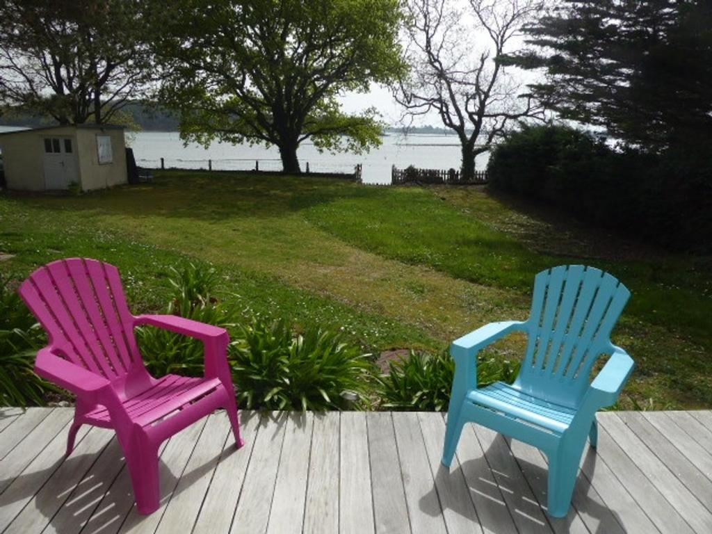 2 sillas sentadas en una terraza con vistas al agua en Maison Sainte-Hélène (Morbihan), 4 pièces, 6 personnes - FR-1-397-21, en Locoal