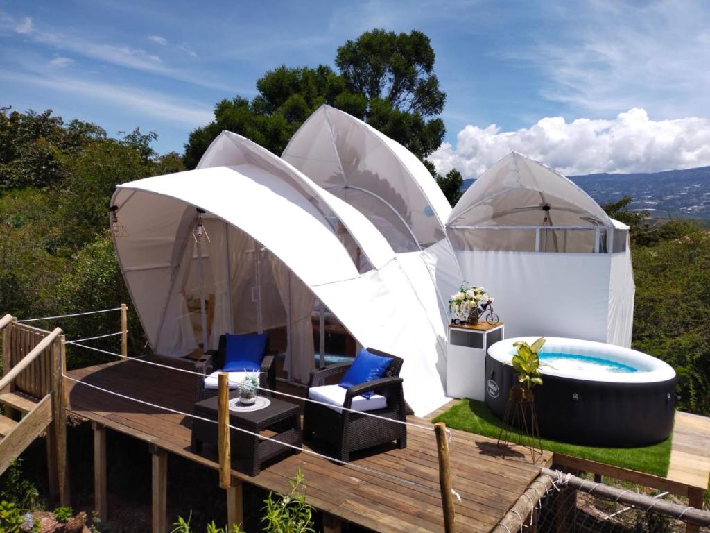 Origen Glamping en Villa de Leyva في فيلا دي ليفا: خيمة فاخرة مع حوض استحمام ساخن وخيامان
