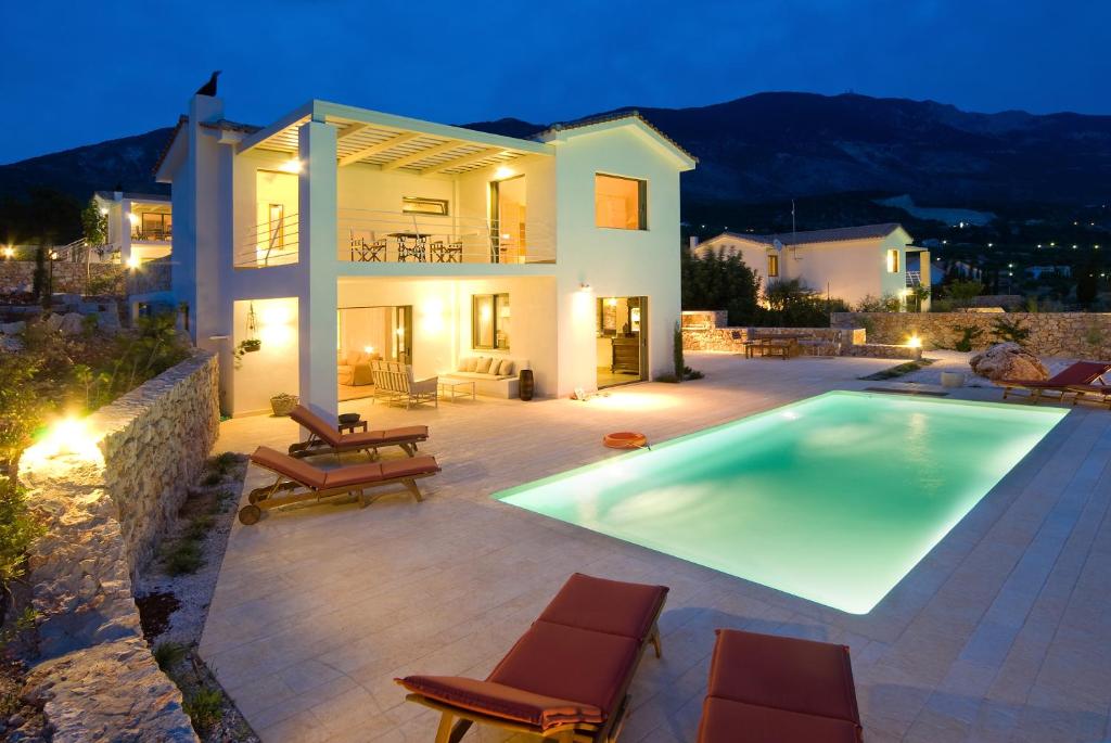 a villa with a swimming pool in front of a house at Ideales Resort in Trapezaki