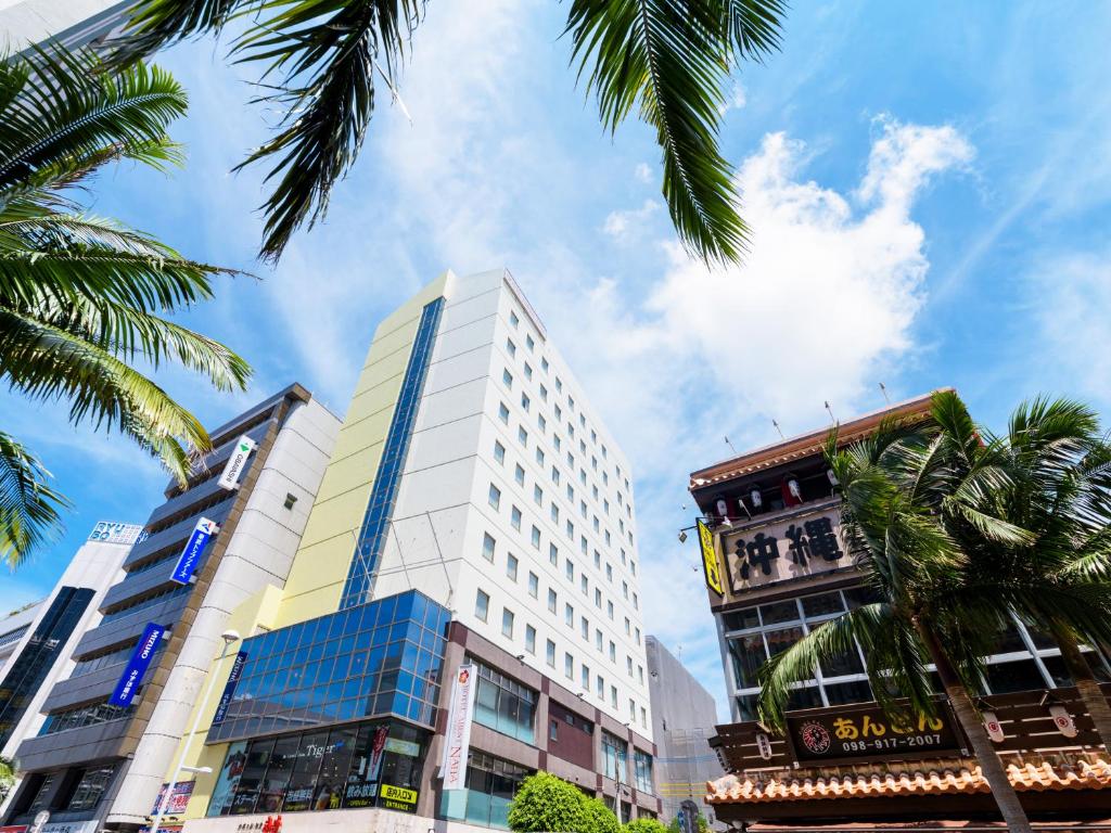 a tall white building in a city with palm trees at Hotel Abest Naha Kokusaidori in Naha