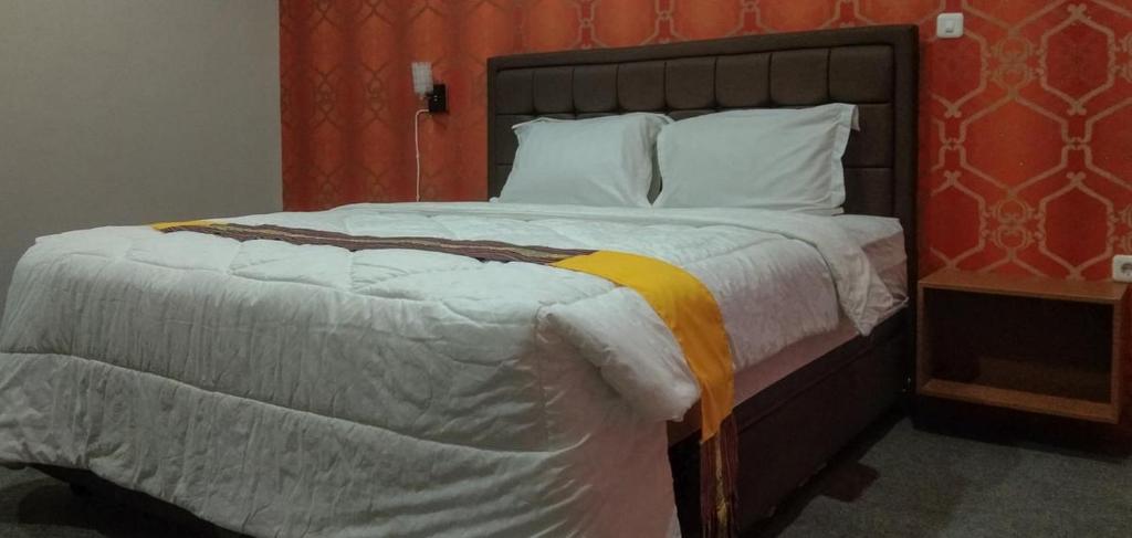 ein Schlafzimmer mit einem großen Bett und einer orangefarbenen Wand in der Unterkunft Edhotel Kusuma Atambua Mitra RedDoorz in Tatakiren