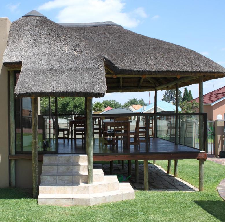 a gazebo with tables and chairs with a straw roof at Die Suidwester Gastehuis in Parys