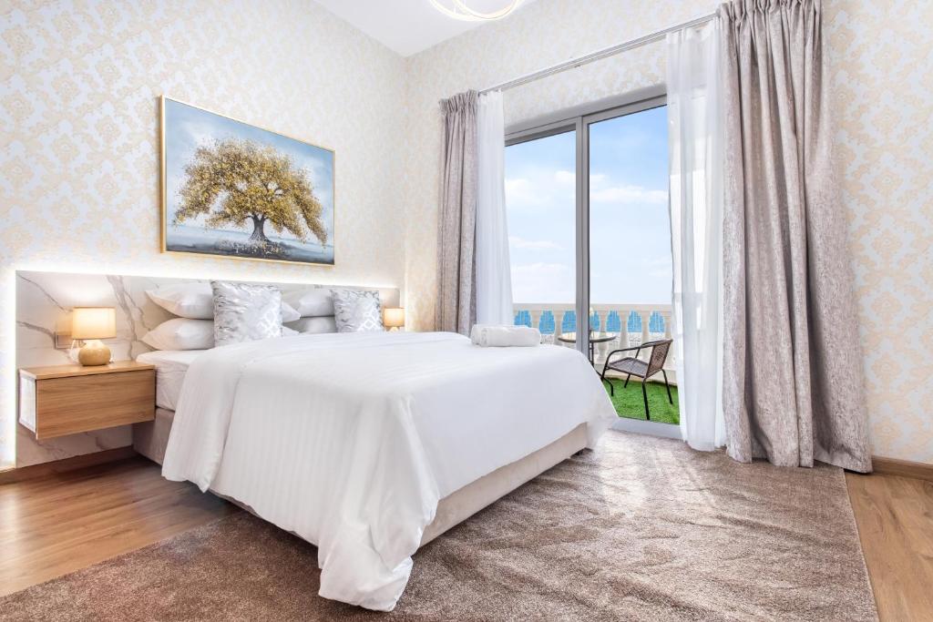 a bedroom with a large white bed and a large window at Live and experience a stunning Sea View Studio in Ras al Khaimah