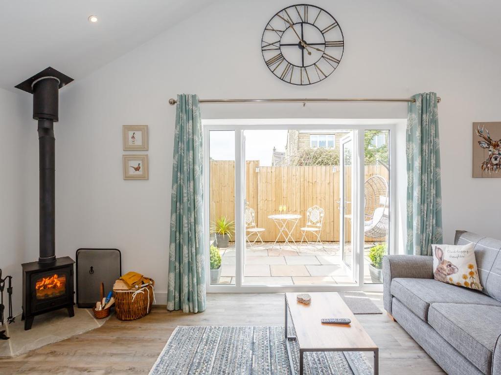 a living room with a couch and a clock on the wall at Eames Cottage in Cowling
