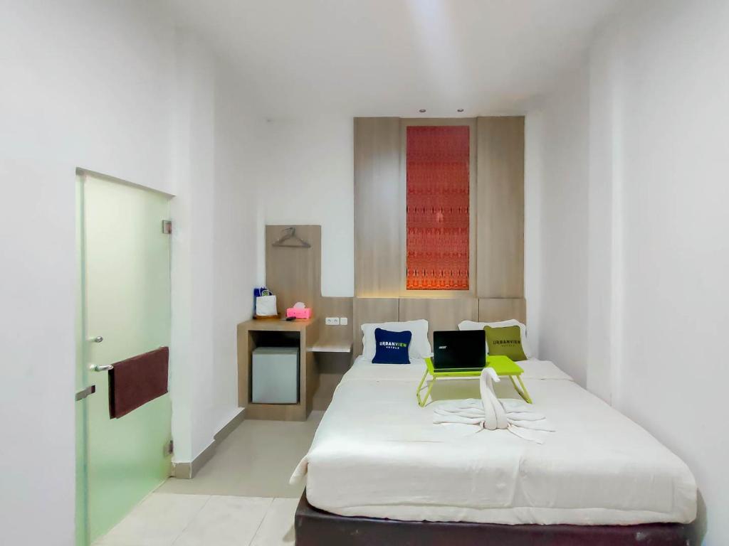 a bedroom with a bed with a laptop on it at Urbanview Hotel Bagoes Sintang by RedDoorz in Sintang