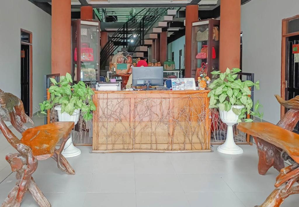 a store with a wooden counter with plants and chairs at Urbanview Hotel Bagoes Sintang by RedDoorz in Sintang