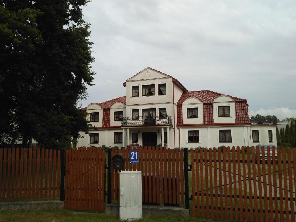 a large house behind a fence with a gate at Dworek Morski in Kołobrzeg