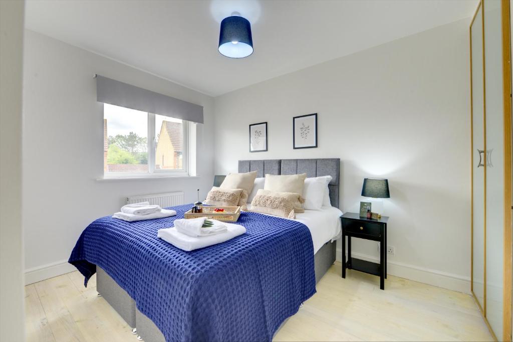 a bedroom with a bed with a blue comforter at The Bernstein House 'Green Award' A Calm & Beautiful Executive House I Spacious Garden w Furniture I Parking I eco-Short Term Let by SILVA in Milton Keynes