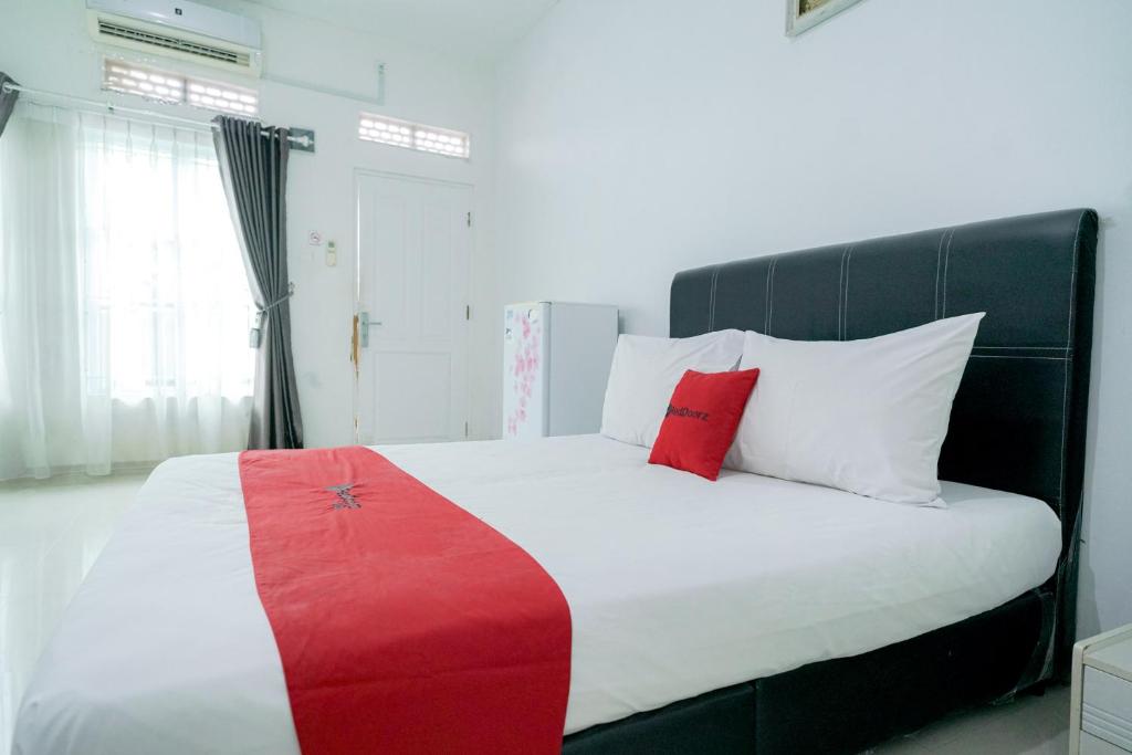 a bedroom with a large bed with red and white pillows at RedDoorz Syariah near RS Awal Bros Batam in Nagoya