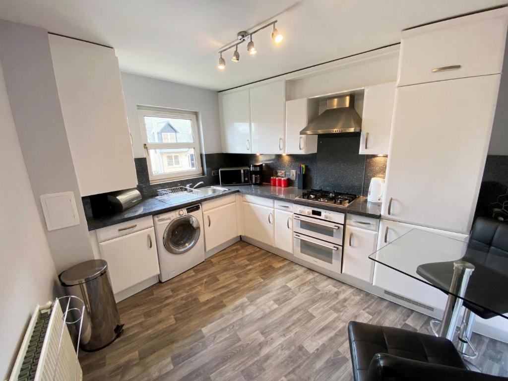 a kitchen with white cabinets and a washer and dryer at NEW Super 2 Bedroom Flat in Falkirk in Falkirk
