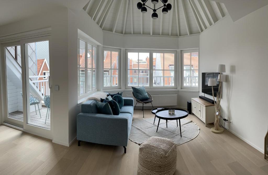 ein Wohnzimmer mit einem blauen Sofa und einem TV in der Unterkunft Residentie Square - Nieuwbouw - 50 m van de zee in Knokke-Heist