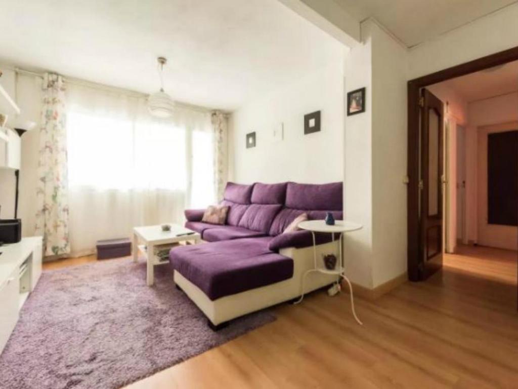 a living room with a purple couch and a table at La Adicidad de Castellón in Móstoles