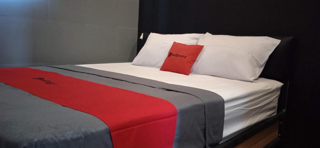 Una cama con una almohada roja encima. en RedDoorz @ Jalan Raya Baturaden 2, en Rempawah