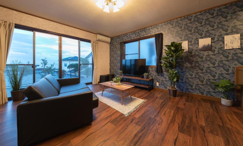 een woonkamer met een bank en een tv bij HAKUDAKU no YUYA in Beppu