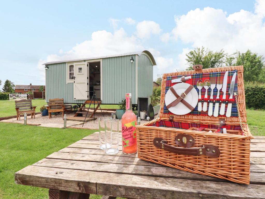 a picnic table with a basket of drinks and a bottle at Honeybee Lodge in Woodhall Spa