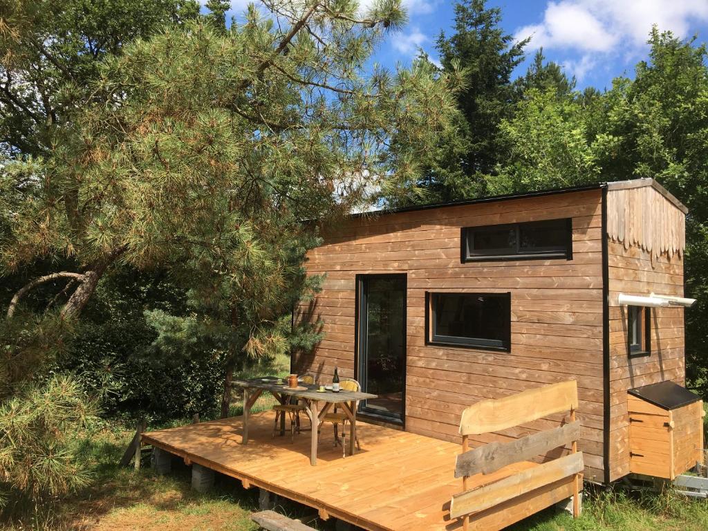 a small wooden cabin with a table on a deck at La pause tiny in Ploërmel