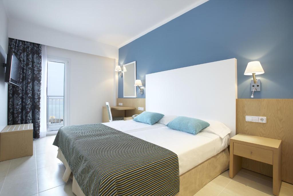 a bedroom with a large bed with blue walls at Universal Hotel Marqués in Colònia de Sant Jordi