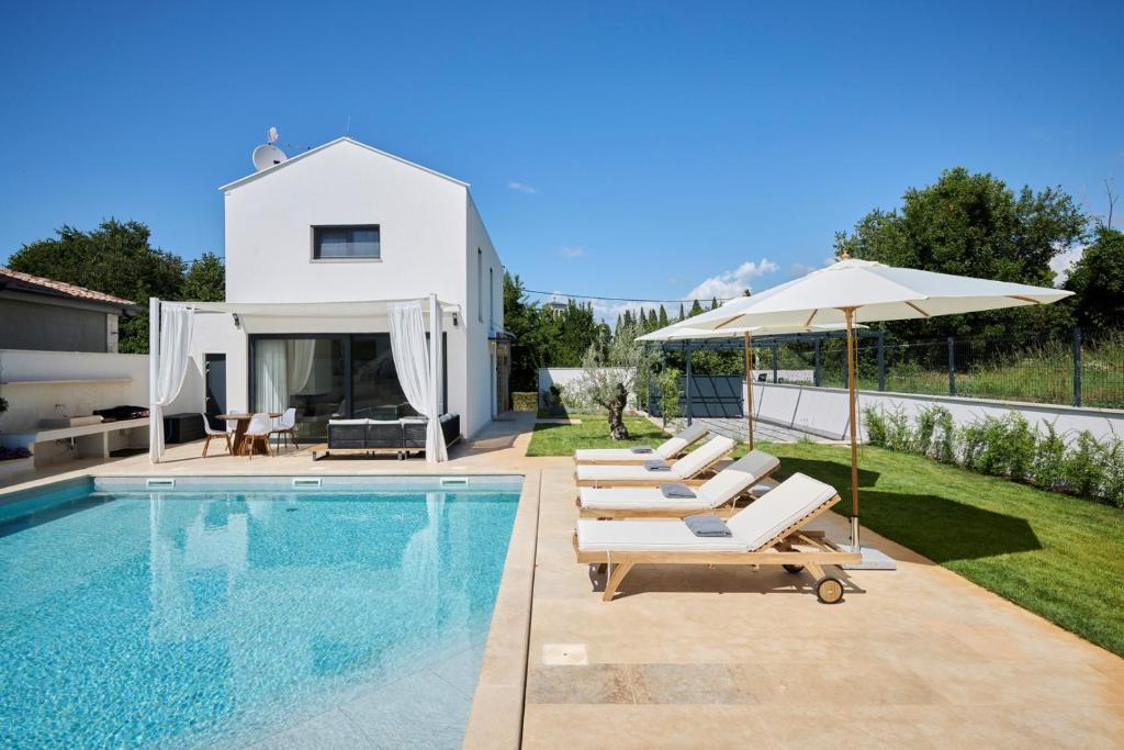 einen Pool mit Liegestühlen und Sonnenschirm und ein Haus in der Unterkunft Villa Pura Vida in Materada