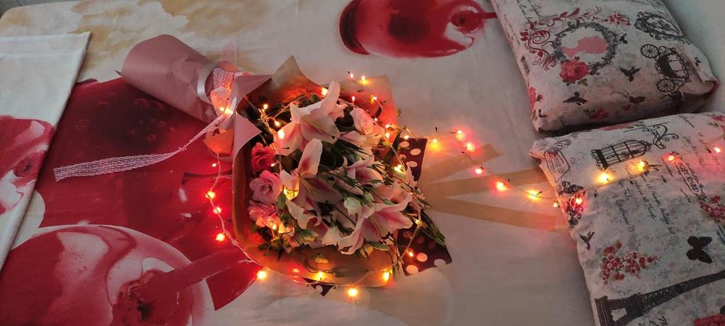 a bouquet of flowers on a bed with lights at Apartman Jasna, in Pirot