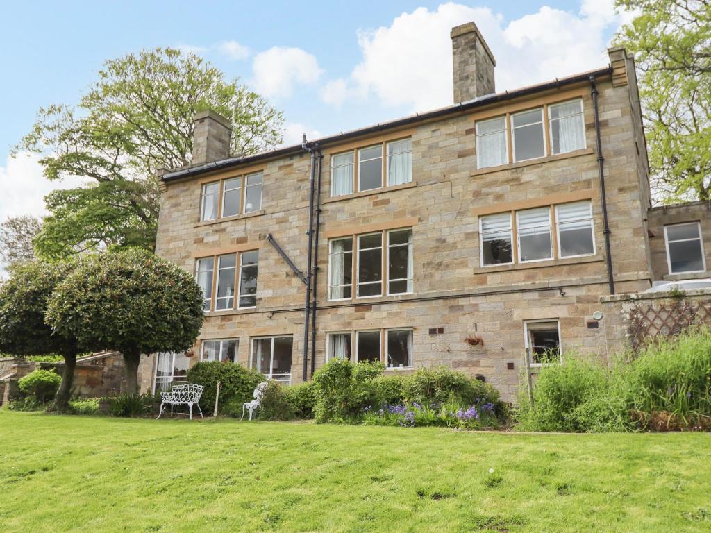 an old stone house with a lawn in front of it at The Garden Apartment in Whitby