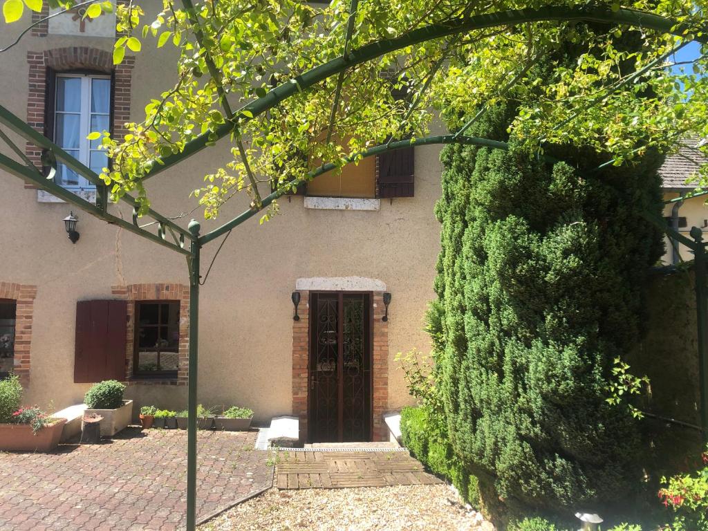 een gebouw met een deur en een grote groene struik bij Villa Capucine in Aubigny-sur-Nère