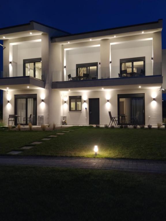 ein Haus in der Nacht mit Rasen davor in der Unterkunft Flâneur apartments in Ormos Panagias