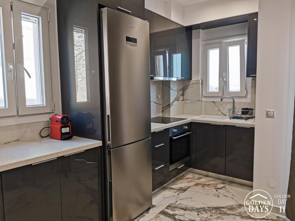 a stainless steel refrigerator in a kitchen with black cabinets at Golden Days villas in Sívas