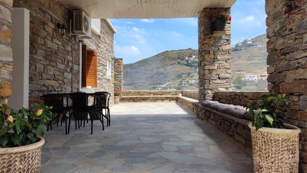 a patio with chairs and a table in a stone building at Kea Petra Studios in Korissia