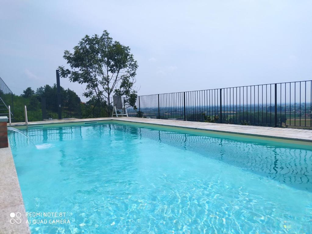 una piscina con acqua blu di fronte a una recinzione di B&B Villa Antilia a Busca