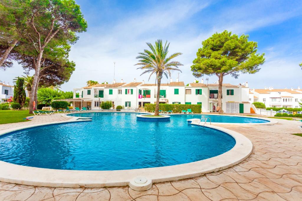 una piscina con árboles y casas en el fondo en Las Brisas 11 en Ciutadella