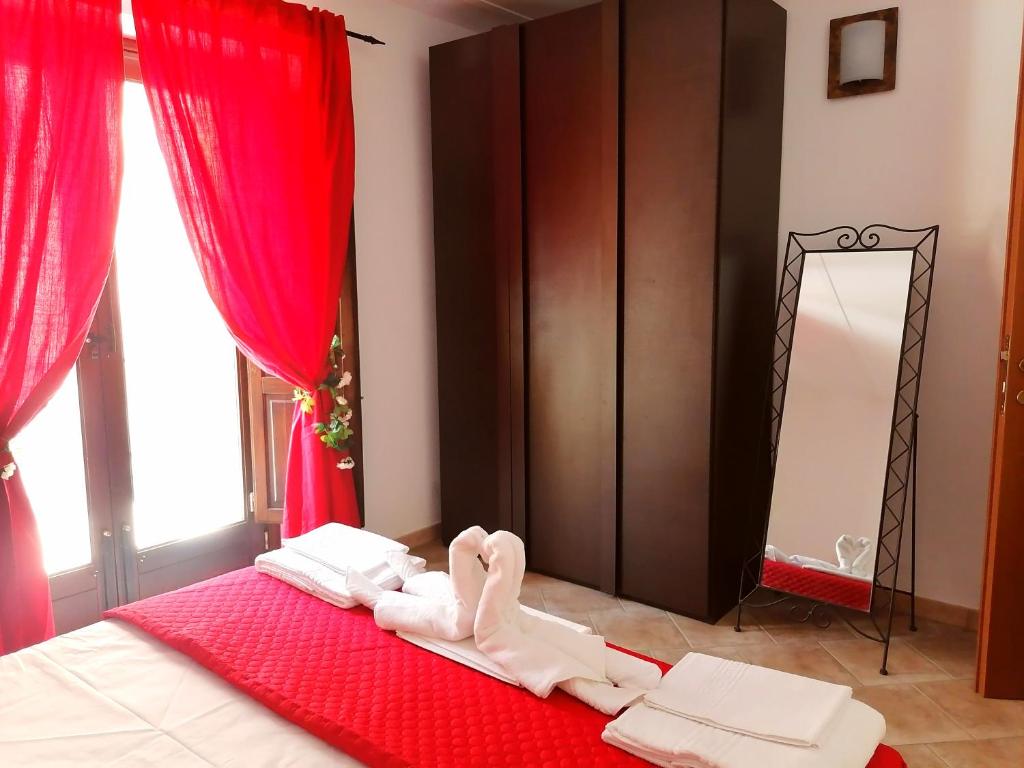 1 dormitorio con 1 cama con cortinas rojas y espejo en Le Rose di Maria, en Trapani