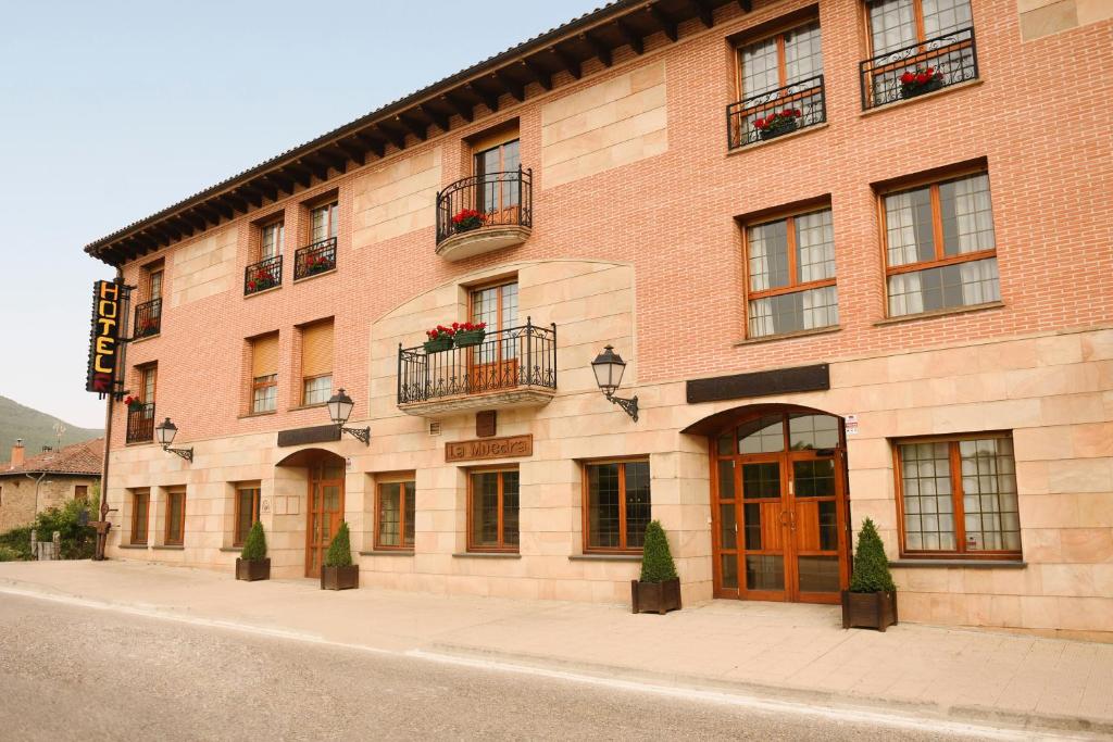 a brick building with windows and balconies on a street at Hotel Rural Villa de Vinuesa in Vinuesa
