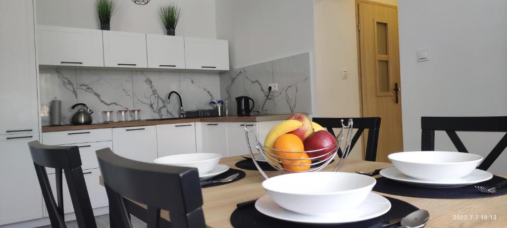 una cocina con mesa y un bol de fruta en Apartament Magnolia -centrum, en Tarnów