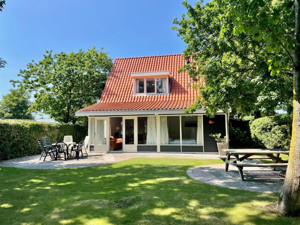 a house with a table and chairs in a yard at Vakantiehuis Zonlicht in Zoutelande