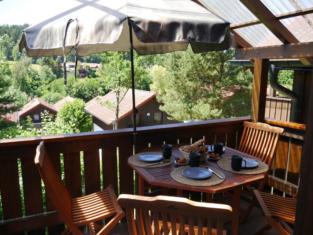 a wooden table on a deck with an umbrella at Yimi Ferienwohnung in Grafenwiesen