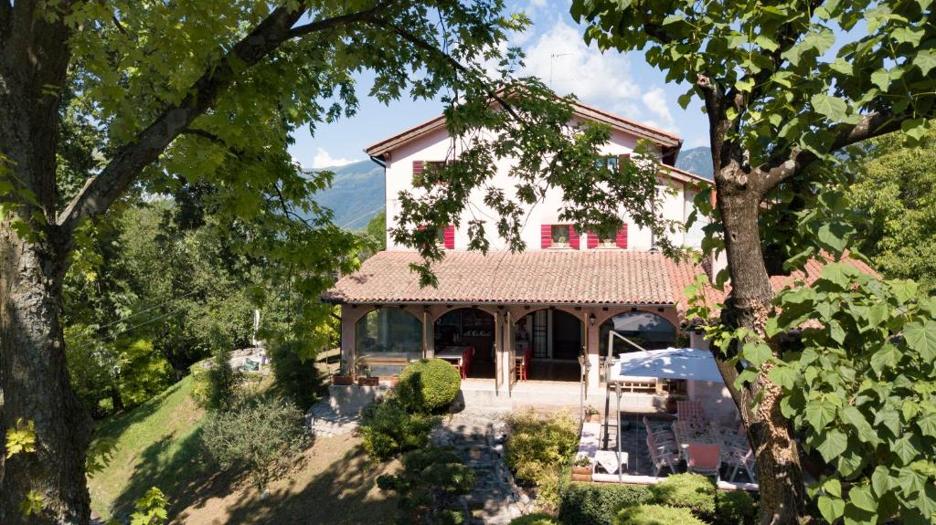 una casa grande con techo rojo y árboles en B&B Four Winds, en Follina