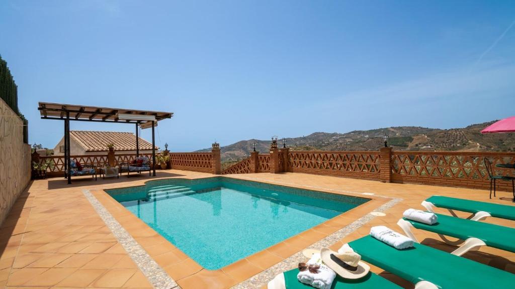 uma grande piscina com cadeiras e um deque em Villa Fuente Luz Frigiliana by Ruralidays em Frigiliana
