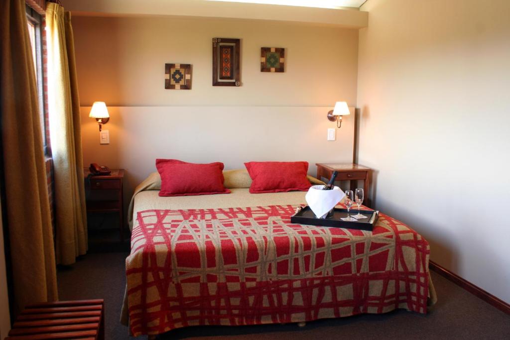 a hotel room with a bed with red pillows at Hosteria Posta Sur in El Calafate