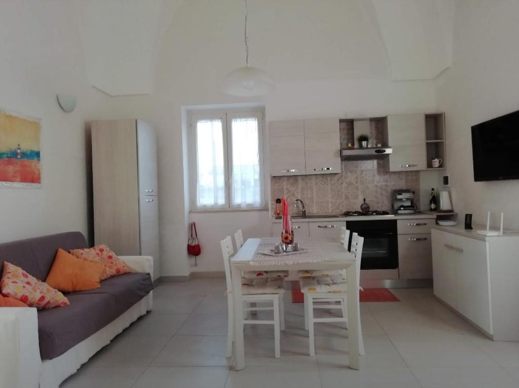 a kitchen and living room with a table and a couch at La Casetta 22 in Andrano