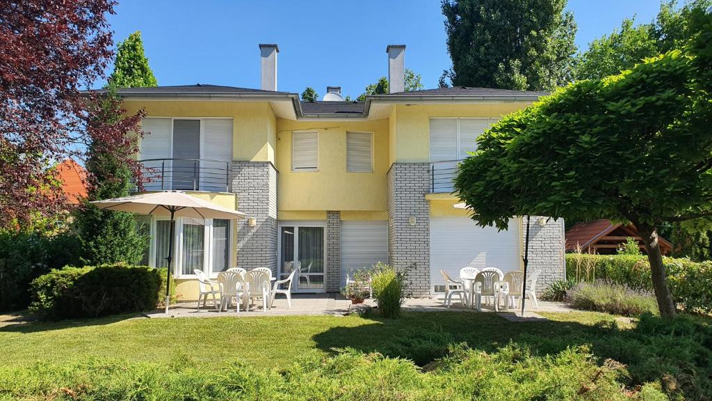 a yellow house with chairs and an umbrella at Holiday home in Szantod - Balaton 20221 in Szántód