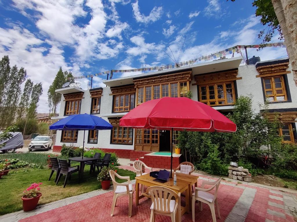 a house with a table and two umbrellas at Jig Gyas Guest House in Leh