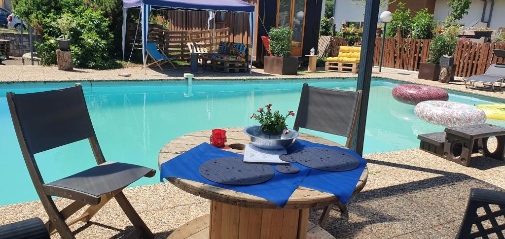een tafel en stoelen voor het zwembad bij Villa Perran Résidence in Thonon-les-Bains
